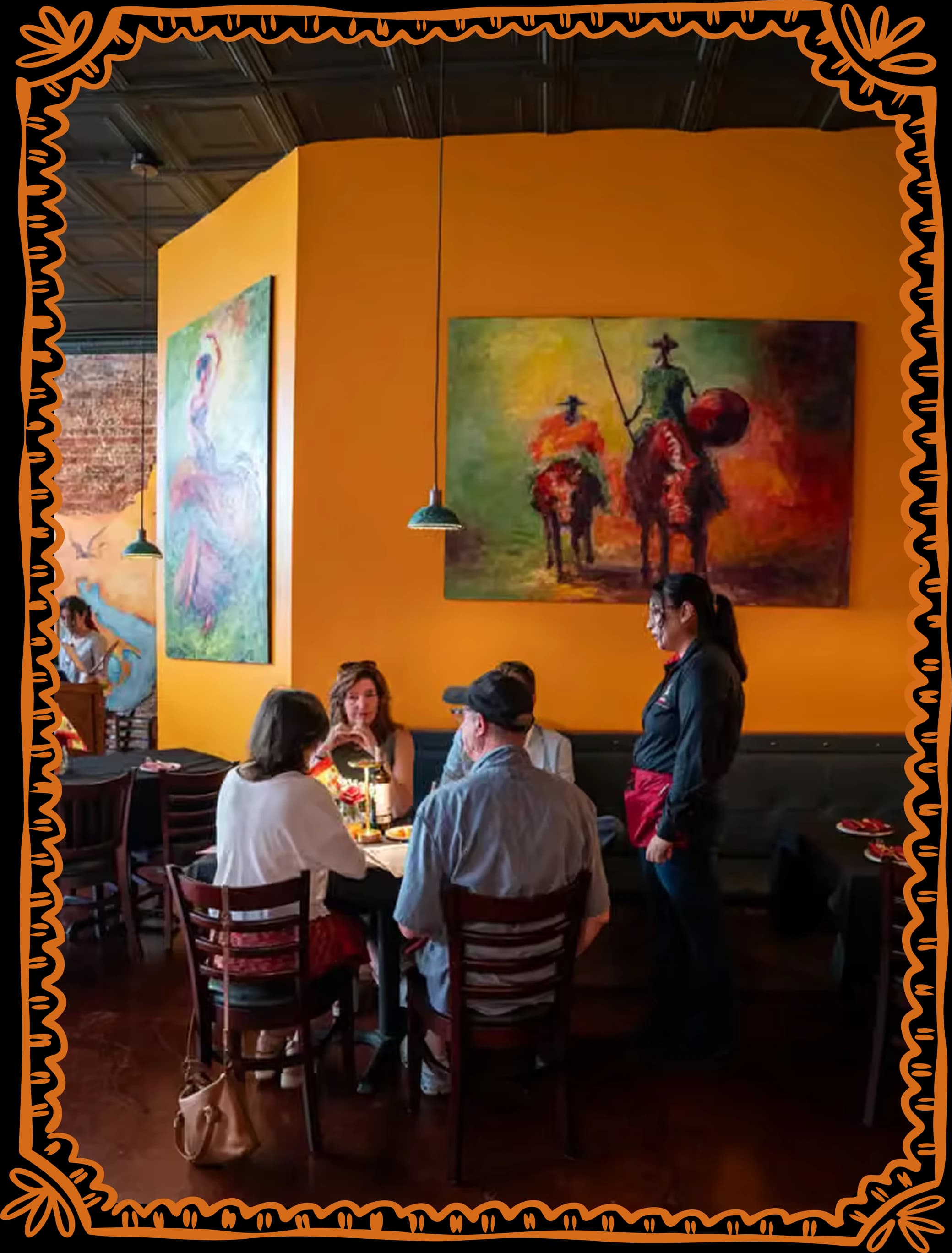 A table of guests mid-meal in the ochre dining room, under the large painting of Don Quixote and Sancho, with a server beside them.