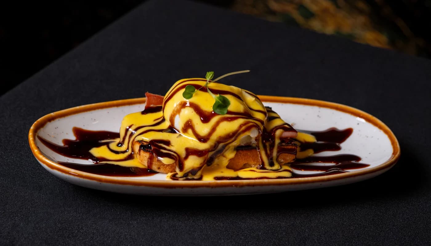La Bella Benedict: poached eggs under hollandaise on toasted bread, dusted with paprika and set beside a dressed salad.